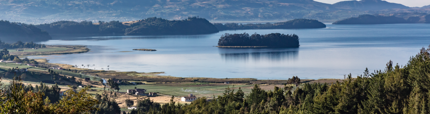 Paisaje rural con lago de fondo y una pequeña isla en medio